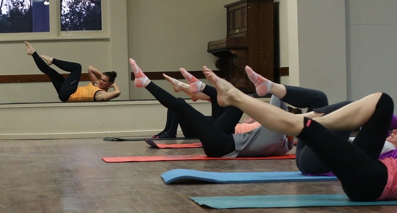 Participants practising Pilates mat exercises in a group class